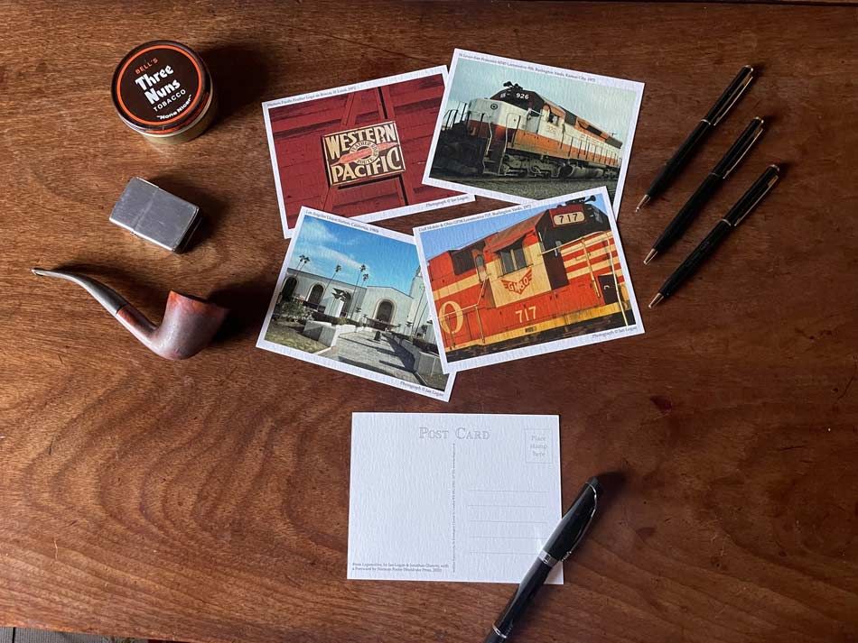 Postcards are laid out on a table, with one selected for writing. 