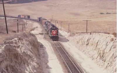 In this colour photo from the 1980s Southern Pacific’s SD70 locomotive 8491 hauls cargo up a gradient in the New Mexico desert.