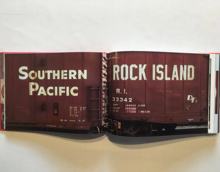 In this colour photograph taken by Ian Logan in the 1970s, boxcars of the Southern Pacific and Rock Island Lines stand cheek by jowl in the freight yards at Kansas City, the names of the companies painted in huge white sans serif capitals on the rusty brown of the cars. 