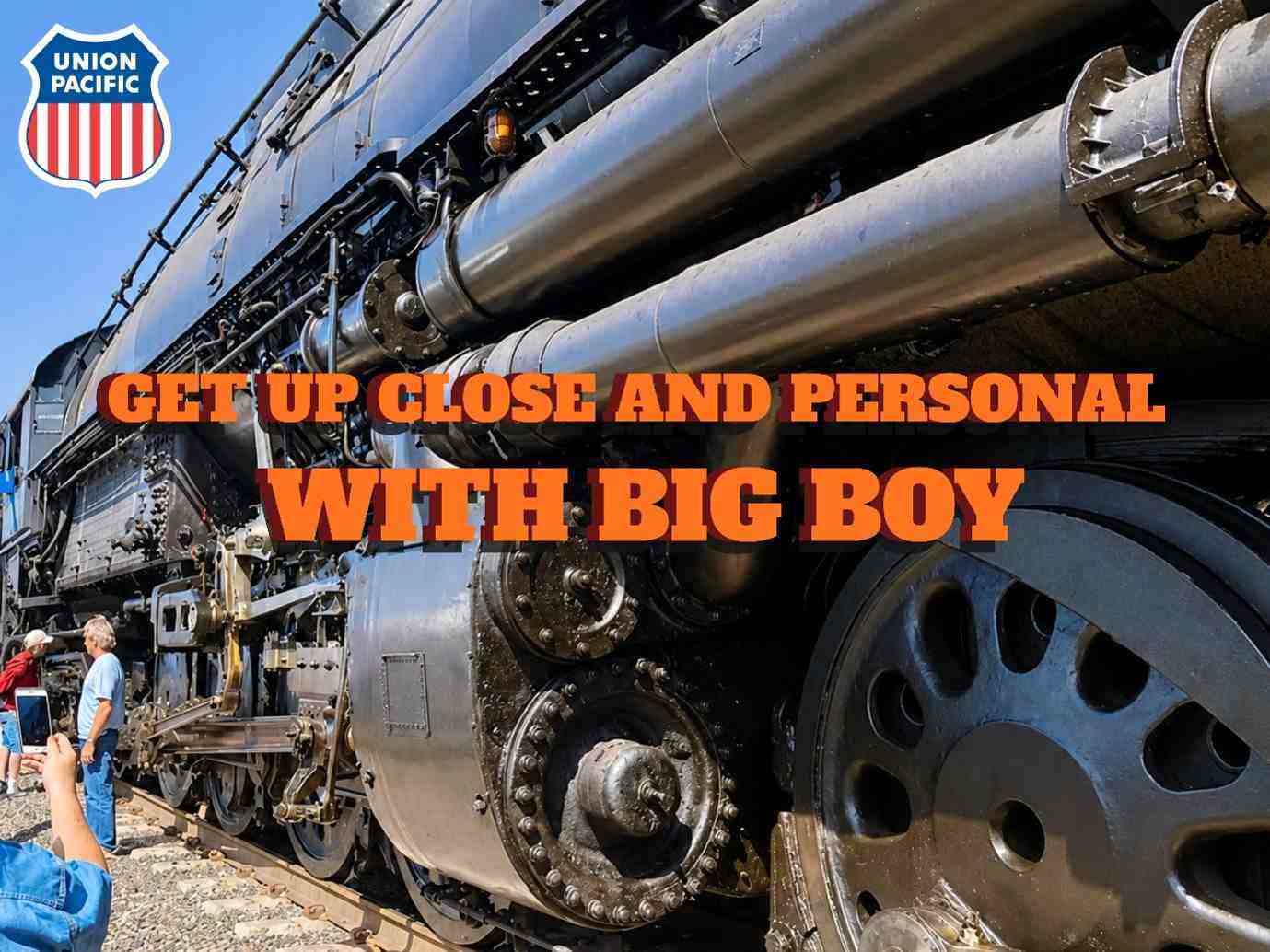 A close-up view of Union Pacific Big Boy 4014 steam locomotive focusses on its massive driving wheels and cylinders and carries the legend ‘Get Up Close and Personal with Big Boy.’