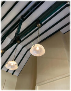 Glass lanterns hang from a wooden cross beam inside Eynsford Station.