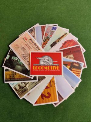 In this colour photo, 15 postcards are arranged in a circular fan on a green background. Another postcard illustrating the cover of Logomotive sits in the centre.