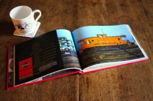 Logomotive lies open beside a cup of coffee, displaying a double-page spread on the Illinois Central Gulf railroad. 