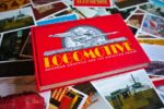 Ian Logan’s book Logomotive lies on an array of postcards created from period photographs and ephemera. 