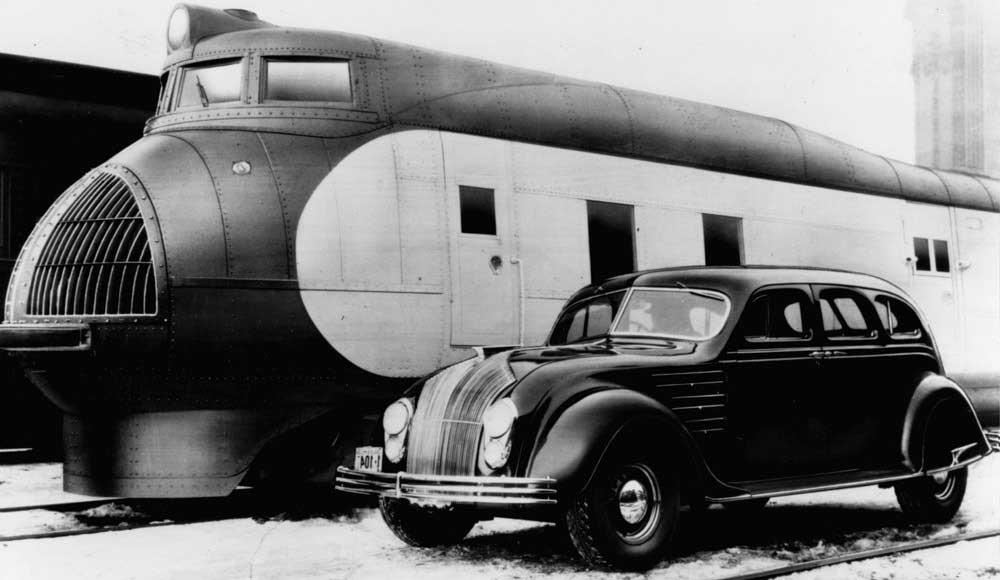 In this black-and-white promotional photograph reflecting the design interests of Norman Foster, the Chrysler Airflow automobile appears alongside the Union Pacific’s M-10000 diesel express