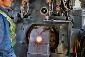 In this colour photograph a crew member has opened the spy hole into the firebox to assess the state of the fire.
