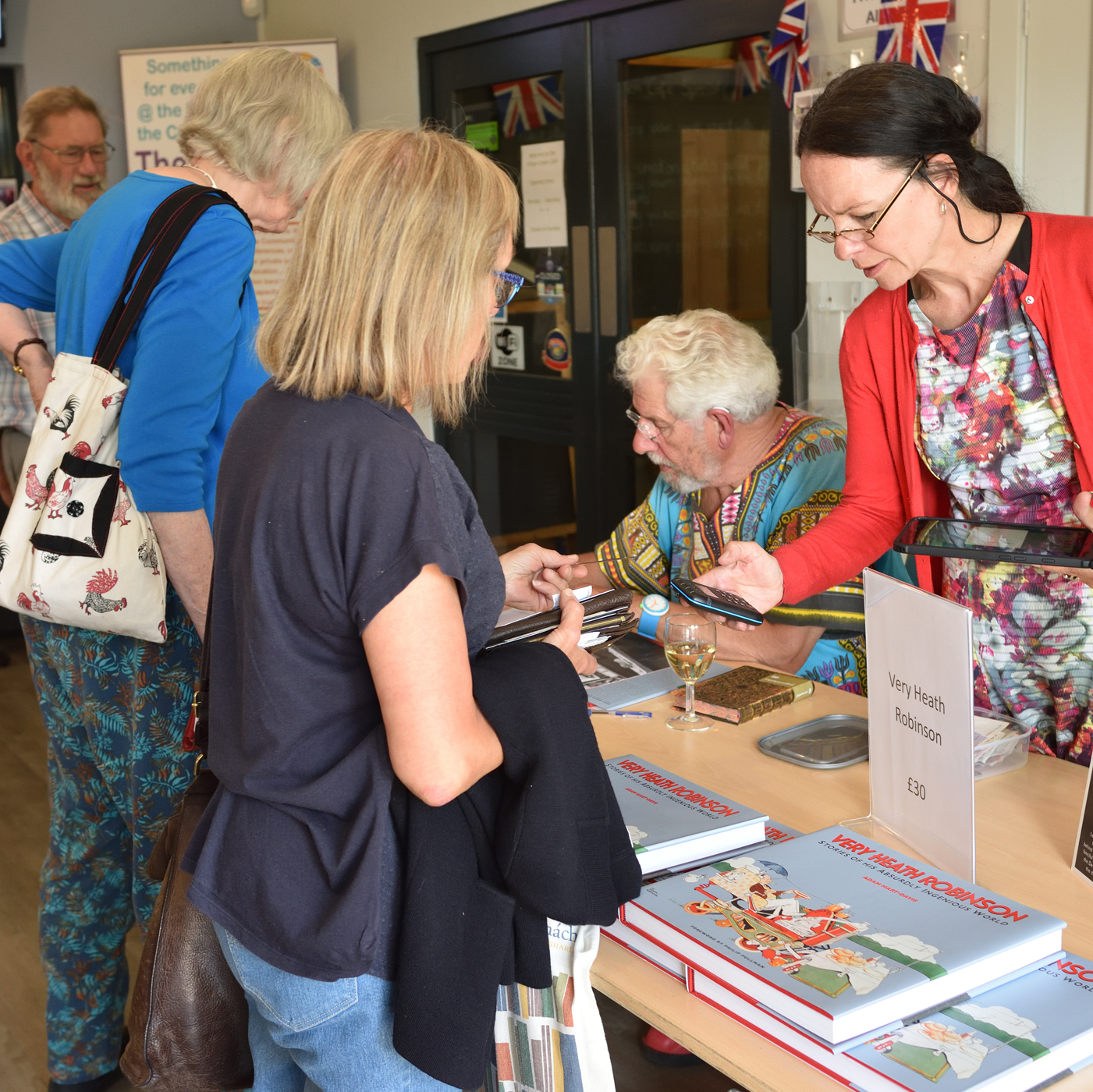 Photograph of Adam Hart-Davies signing books.
