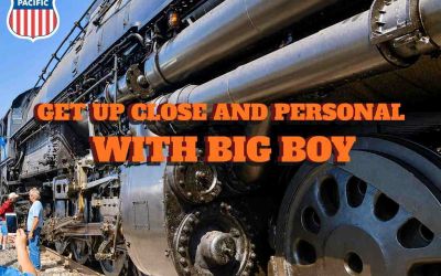 A close-up view of Union Pacific Big Boy 4014 steam locomotive focusses on its massive driving wheels and cylinders and carries the legend ‘Get Up Close and Personal with Big Boy.’