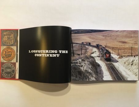 In this colour photograph taken in the 1970s by Ian Logan, author of Logomotive, a Southern Pacific GP 30 diesel locomotive draws a long train of boxcars and flat cars up a pass in the New Mexico desert, with two additional locomotives providing power immediately behind. and telegraph poles following the track. The company’s SP logo is picked out in white against the company’s ‘bloody nose’ livery. 