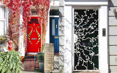 These photographs of two doors side by side were taken by Cath Harries. The door on the left is red with a gold pattern and red leaves hanging over it. The door on the right is black with white wrought-iron tendrils snaking across it and is bordered by a white frame.