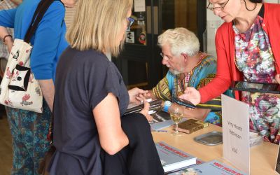 Photograph of Adam Hart-Davies signing books.