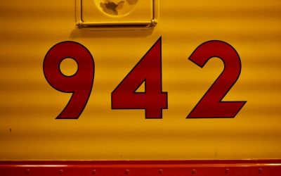 In this colour photograph, the number of a Union Pacific EMD E8 Diesel Locomotive ‘942’ appears in red sans-serif font against a yellow background.
